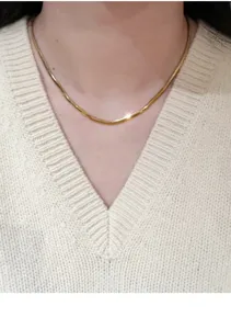 Detailaufnahme der goldenen Schlangenkette als eleganter Halsschmuck im Nahfokus.