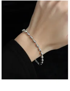 Nahaufnahme Detailansicht eines funkelnden silbernen Perlenarmbands am zarten Handgelenk.