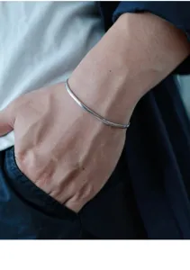 Close-up detail of sterling silver snake chain bracelet worn on wrist, exquisite jewelry.