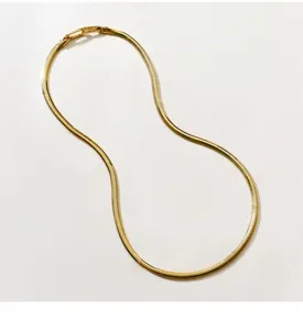 Detailaufnahme einer goldenen Schlangenkette, filigranes Fischgrätmuster, glänzende Oberfläche.