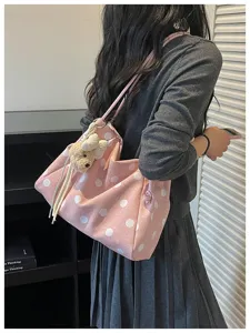 Casual pink polka dot canvas shoulder tote bag with cute plush bear pendant detail.