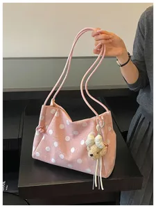 Close-up detail of the pink polka dot shoulder bag with cute bear charm and thin straps.