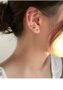 Nahaufnahme im Detail von funkelnden bunten Zirkon-Ohrringen am Ohr-Piercing.