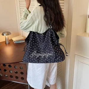 Détail de sac cabas d'été, tissu noir avec empreintes de pattes blanches et texte.