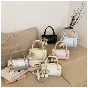 Detail view of multi-color minimalist cylinder pillow shoulder bags with pearl tulip charms.