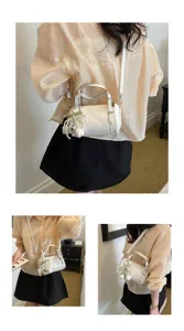Detail view of fashionable white mini pillow bag with pearl tulip charm and shoulder strap.