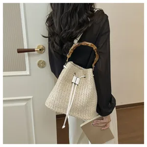 Détail sac seau en paille, sac à main de plage tressé avec poignée en bambou.