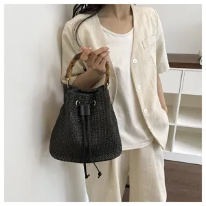 Vue détaillée du sac seau en paille tressée noire pour femme avec poignée en bambou.