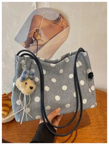 Stylish denim polka dot shoulder bag with cute bear pendant for women commuting daily use.