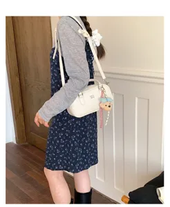 White shoulder bowling bag for women, stylish commuting crossbody handbag with cute bear pendant.