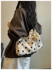 Detailed scene shot of a minimalist polka dot tote bag with cute bear charm, carried on shoulder.