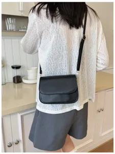 Detail shot of minimalist black women crossbody bag, showcasing fine leather texture and hardware.
