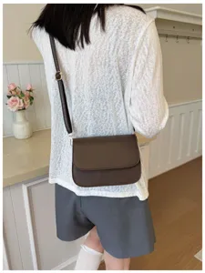 Minimalist women crossbody shoulder bag detail showcasing dark brown leather design.
