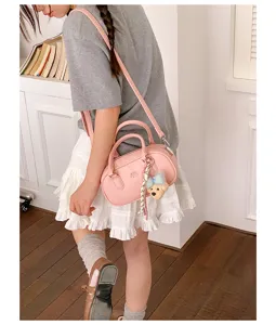 Stylish pink bowling shoulder bag for women, commuter handbag with cute bear pendant and strap.