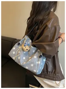 Close-up detail of casual polka dot canvas shoulder tote bag with cute plush bear pendant.
