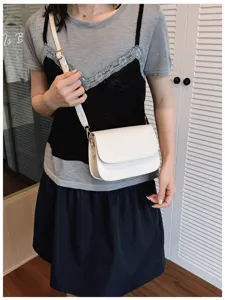 Detail view of a minimalist white women's crossbody shoulder bag worn casually, stylish accessory.