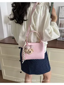 Detail shot of the elegant pink leather bucket bag with cute bear pendant and silk scarf.