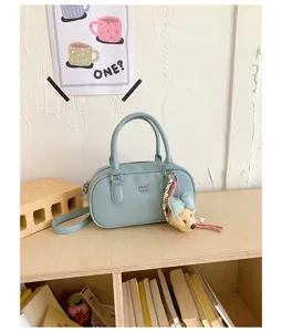 Fashionable light blue bowling shoulder bag for women, commuter handbag with cute plush bear pendant.