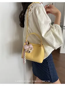 Stylish yellow bucket bag for women, versatile shoulder crossbody handbag with cute bear charm.