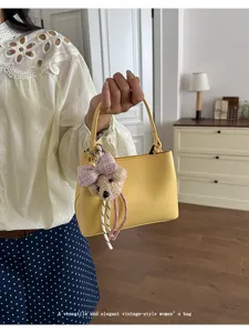 Elegant yellow women handbag with cute bear keychain for casual commuting and daily wear.