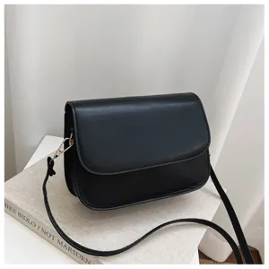 Detail view of minimalist black women crossbody bag, sleek flap design with slim strap.