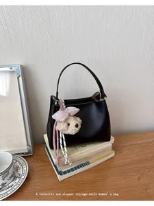 Stylish black top-handle bucket bag for women, featuring a cute teddy bear charm and elegant design.