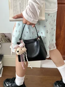 Women's black PU leather bucket handbag, stylish shoulder commute bag shown in hand.