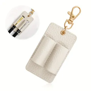 Detail shot of the beige leather double pen holder keychain with gold clasp and keyring.