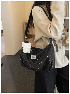 Vista dettagliata della grande borsa a tracolla nera stellata con grazioso peluche di orsetto.