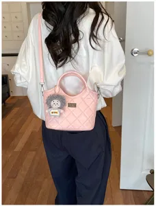 Élégant sac à main matelassé rose pour femme avec pendentif poupée en peluche et poignée.