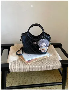 Vue détaillée d'un sac à main noir matelassé chic avec un joli pendentif poupée en peluche.