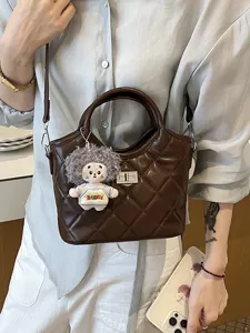 Sac bandoulière matelassé vintage chic pour femme avec pendentif poupée et verrou métallique.