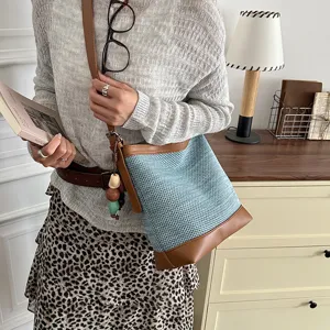 Summer casual woven bucket bag detail, stylish blue mesh and brown leather shoulder bag.