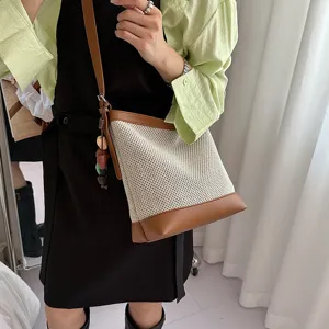 Summer women woven bucket bag, stylish crossbody shoulder bag with leather trim and pendant.