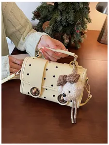 Chic yellow polka dot crossbody bag with cute plush bear pendant and elegant lock design.