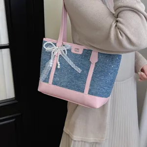 Detailed view of the casual denim tote bag featuring a cute pearl lace bow and pink trim.