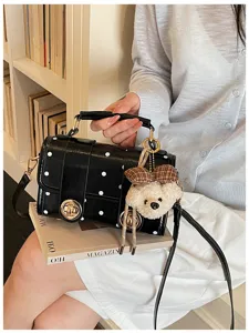 Detailed view of black polka dot crossbody handbag featuring a cute plush bear keychain charm.
