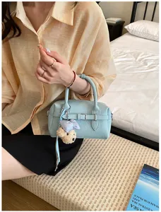 Primo piano della borsa Boston azzurra che mostra consistenza, fibbia e ciondolo orsetto.