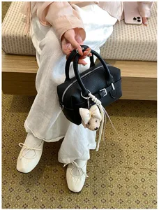 Vista dettagliata di una borsa a mano boston nera in pelle con grazioso ciondolo.