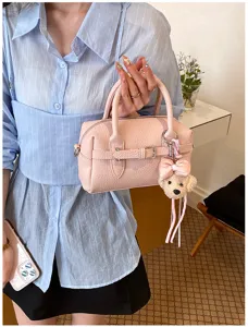 Primo piano dettagliato della borsa Boston rosa elegante con ciondolo a forma di orsetto.