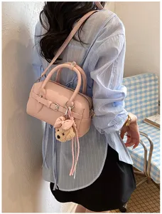 Dettaglio borsa Boston in pelle rosa con grazioso ciondolo a forma di orsetto.