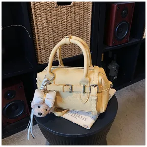 Vista di dettaglio di un'elegante borsa a mano Boston gialla con ciondolo e tracolla.