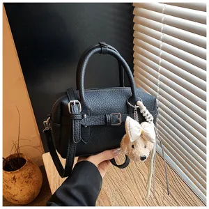 Dettaglio borsa a tracolla Boston nera, elegante borsa in ecopelle con ciondolo a orsetto.