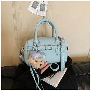 Dettaglio borsa a mano azzurra con fibbia elegante e grazioso ciondolo in peluche morbido.