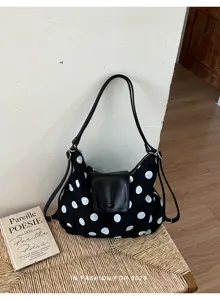 Vista dettagliata della borsa a spalla nera in tela con pois bianchi e patta in pelle.