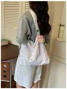 Vue détaillée du sac cabas fourre-tout à pois blancs avec accessoire pendentif ours mignon.