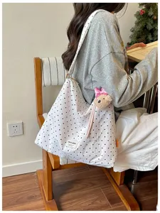 Vue détaillée du sac fourre-tout élégant à pois avec joli pendentif d'ours et large sangle.