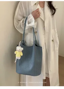 Detailed view of the Korean style woven leather tote shoulder bag with a cute bear pendant.