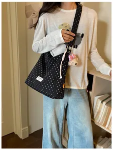 Vue détaillée du sac cabas en toile à pois noirs, avec charmant pendentif ourson et bandoulière.