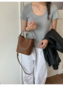 Detailed view of the brown woven leather bucket bag with handle and shoulder strap.